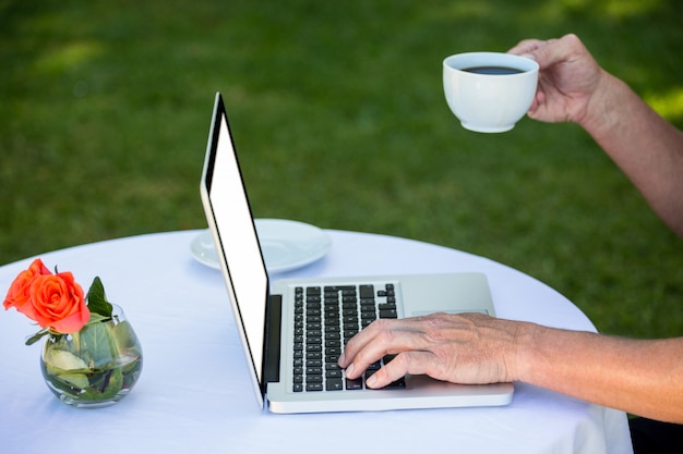 Zufälliger Geschäftsmann unter Verwendung des Laptops und Trinken des Kaffees