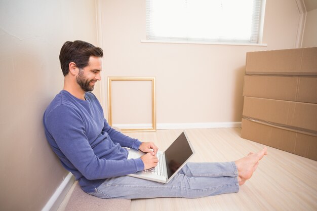 Zufälliger Mann, der Laptop nachdem einziehen verwendet