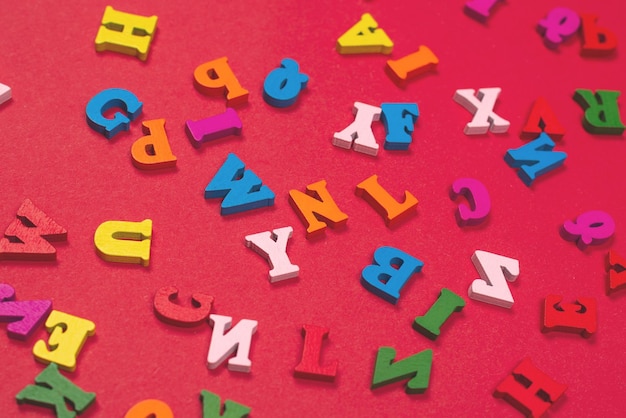 Zufälliges buntes Alphabet auf einem roten Hintergrund bunte Buchstaben