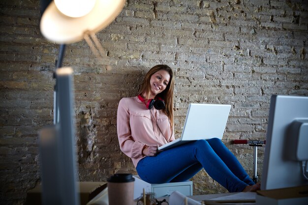 Zufälliges Sitzen der Geschäftsfrau im Büro mit Laptop