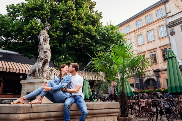 Zufälliges süßes Paar, das auf einem Brunnen sitzt