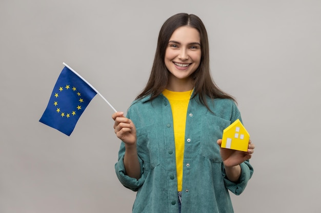 Foto zufrieden mit der europäischen flagge und dem papierhaus, das davon träumt, eine unterkunft in europa zu kaufen