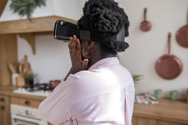 Zufriedene afrikanische Frau in rosafarbener Kleidung in VR-Gläsern