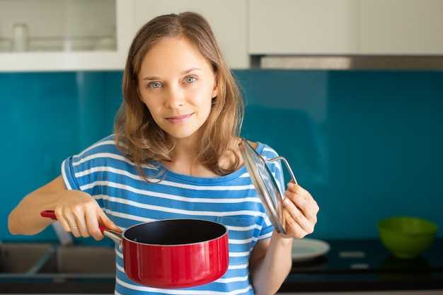 Zufriedene Frau, die Soßen-Wanne kocht und hält