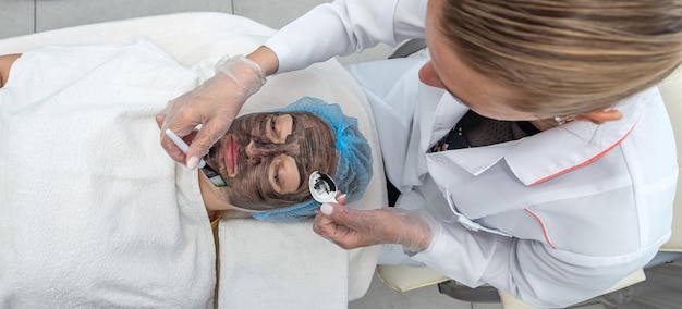 Zufriedene Frau nutzt die Dienste einer professionellen Kosmetikerin in einem Schönheitssalon oder Spa