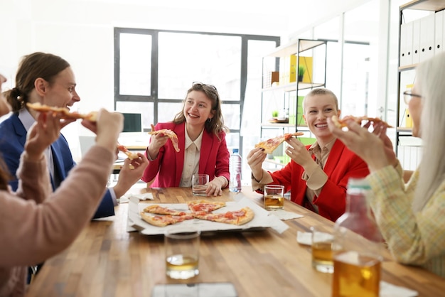 Zufriedene Mitarbeiter des Unternehmens genießen Fastfood während der Pizza-Party im Büro, informelle Kommunikation zwischen ihnen