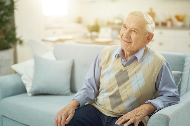 Zufriedener älterer Mann, der sich auf der Couch im Wohnzimmer entspannt