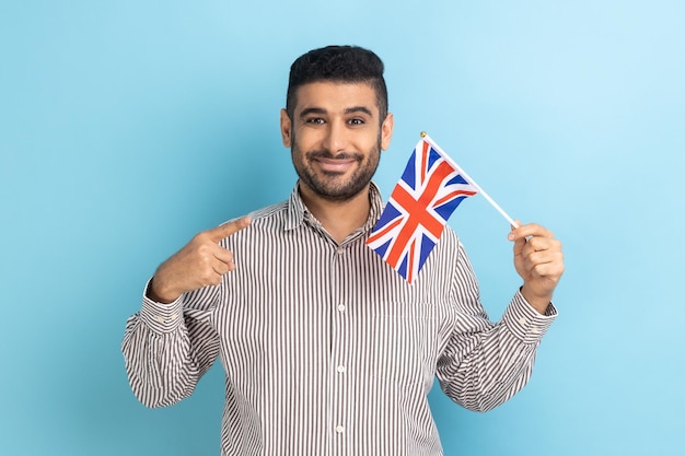 Zufriedener Geschäftsmann mit Bart, der auf die britische Flagge zeigt und Kamera-Patriot anschaut