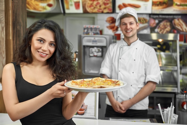 Zufriedener Kunde, der Pizza in Händen hält und im Café aufwirft