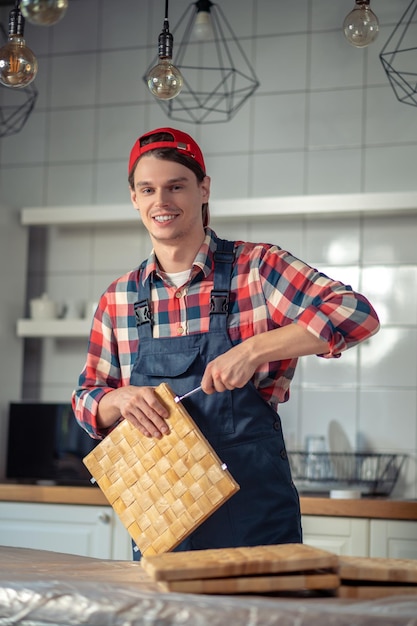 Zufriedener Tischler, der in der Küche eine Strohkiste herstellt