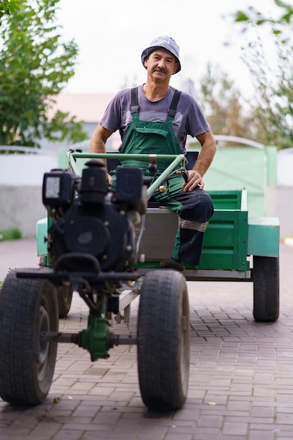 Zufriedenes Bauernporträt, das hinter dem Rad eines zweirädrigen Traktors sitzt