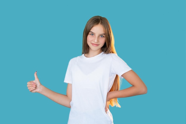 Zufriedenes Mädchen wie Geste Gut gemacht Genehmigungszeichen Porträt einer glücklichen, enthusiastischen, fröhlichen jungen Dame in weißem T-Shirt, die den Daumen nach oben lächelnd zeigt, isoliert auf blauem Kopierraumhintergrund