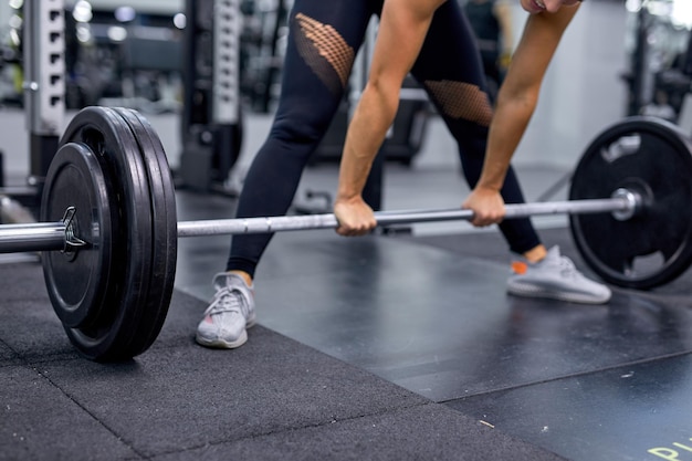 Zugeschnittene junge Bodybuilderin beim Training mit Schwergewichtsstange Fitness-Frau