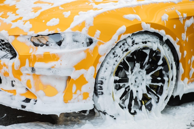 Zugeschnittenes Bild des Rades eines gelben Luxusautos in einer Autowaschanlage mit Selbstbedienung im Freien