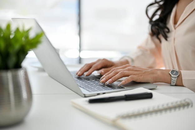 Zugeschnittenes Bild einer asiatischen Geschäftsfrau mit Laptop, die in ihrer Seitenansicht im Büro arbeitet