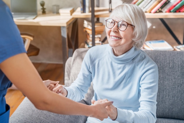 Zugeschnittenes Bild einer professionellen Pflegekraft, die sich zu Hause um ältere Frauen kümmert