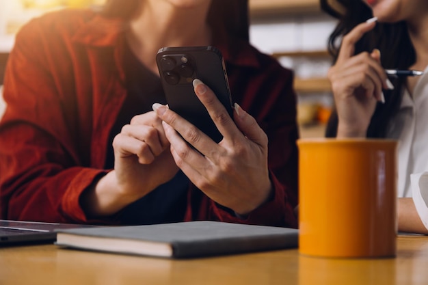 Zugeschnittenes Foto einer asiatischen Freiberuflerin, die eine Kaffeetasse in der Hand hält und am Arbeitsplatz Planung und Analyse des Finanzberichts, Geschäftsplans, Investitionsfinanzierungsanalyse durchführt