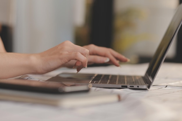 Zugeschnittenes Foto einer asiatischen Freiberuflerin, die eine Kaffeetasse in der Hand hält und am Arbeitsplatz Planung und Analyse des Finanzberichts, Geschäftsplans, Investitionsfinanzierungsanalyse durchführt