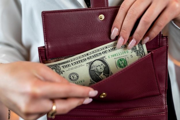 Zugeschnittenes Foto einer Frau, die Geld aus einer offenen Brieftasche verwendet