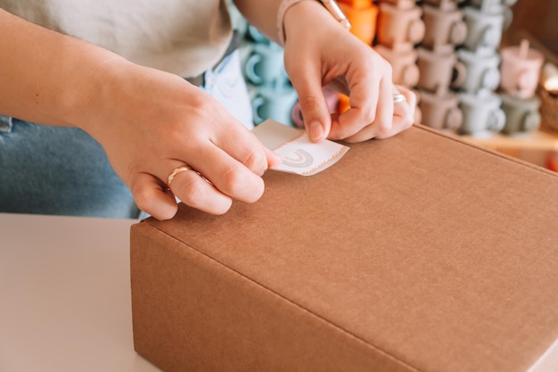 Foto zugeschnittenes foto geschäftsfrau hände verpackung vorbereitung paket für lieferung paket zum käufer silikon-baby-schale-geldbeutel