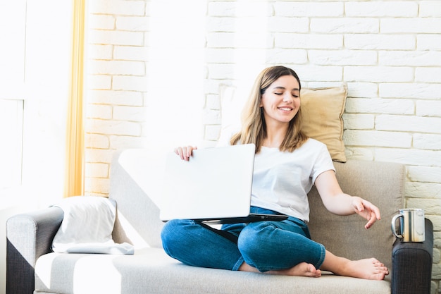 Zuhause arbeiten. junge schöne Frau, die am Laptop auf Sofa zu Hause arbeitet