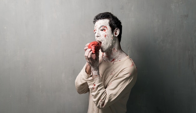 Foto zumbi aterrorizante comendo um coração. feriados do dia das bruxas