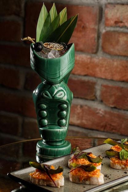 Zumbi de coquetel tropical servido em estilo tiki com frutas e flores um coquetel exótico em um copo tiki fica em um balcão de bar de madeira em um pub ou restaurante para texto