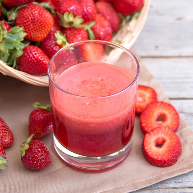 Zumo de batido de fresa fresca y fresas en una mesa de madera de cerca