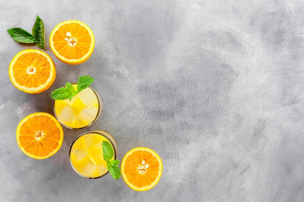 Zumo de naranja frío con hielo sobre piedra gris