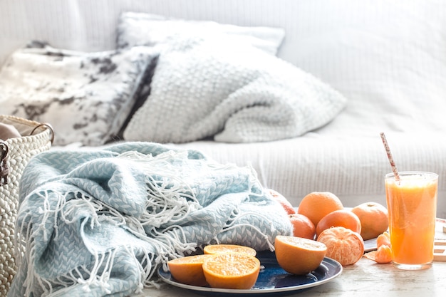 Zumo de naranja orgánico recién cultivado en el interior de la casa, con una manta turquesa y una cesta de frutas.