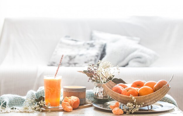 Zumo de naranja orgánico recién cultivado en el interior de la casa, con una manta turquesa y una cesta de frutas.