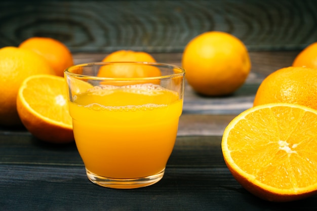 Zumo de naranja en un vaso, naranjas y rodajas de naranja.