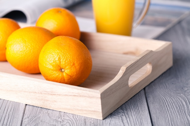 Zumo de naranja en vidrio y fruta fresca en madera