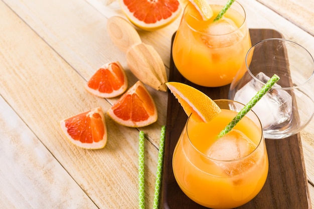 Zumo de pomelo rojo rubí ecológico en vaso pequeño con hielo.