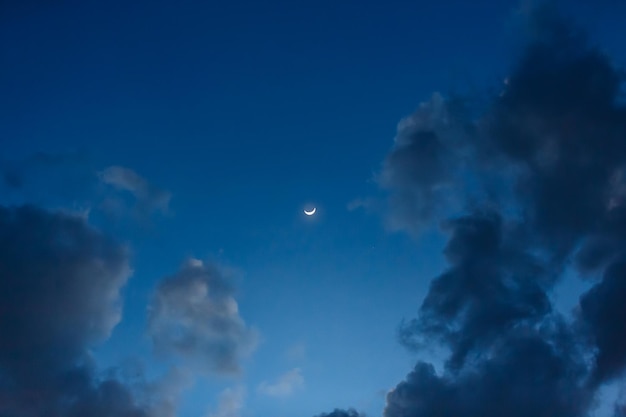 Zunehmender Halbmond mit Erdschein am wolkig blauen Abendhimmel