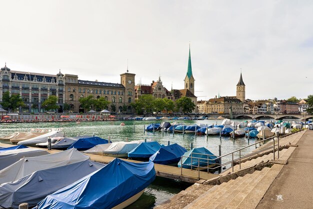 Zurich, Suiza - 2 de septiembre de 2016: Barcos en el muelle del río Limmat, la iglesia de San Pedro y la iglesia de Fraumunster en el centro de la ciudad de Zurich, Suiza.