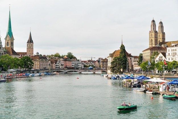 Zurich, Suiza - 2 de septiembre de 2016: Gente en el barco en el río Limmat y tres iglesias principales de Zurich - Grossmunster, Fraumunster y St Peter Church. Suiza