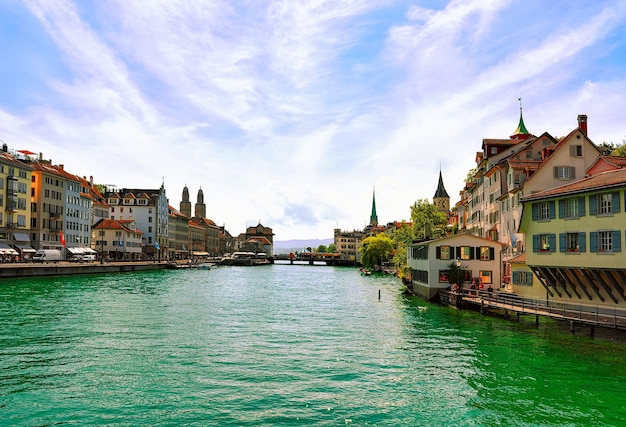 Zurique, Suíça - 2 de setembro de 2016: Cais do Rio Limmat com pináculos de três igrejas principais de Zurique - Grossmunster, Fraumunster e St Peter Church, Suíça