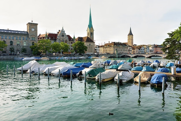 Zurique, Suíça - 2 de setembro de 2016: Igreja de São Pedro, Igreja Fraumunster e barcos no cais do Rio Limmat, no centro da cidade de Zurique, Suíça. Pessoas no fundo