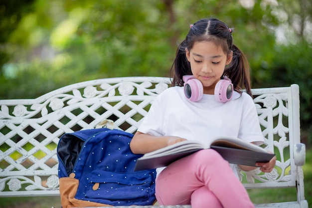 Zurück in der Schule liest ein asiatisches Mädchen ein Buch. Grundschüler lernen nach dem Unterricht Hausaufgaben