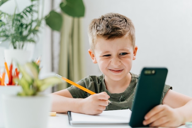 Zurück in die Schule Fernunterricht Online-Bildung Kaukasisches Lächeln Kind Junge studiert nach Hause mit Handy