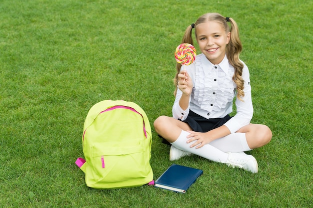 Zurück in die Schule lustiges Kind halten Lutscher Konzept der Bildung gewöhnlichen Lerntag süßes Mädchen