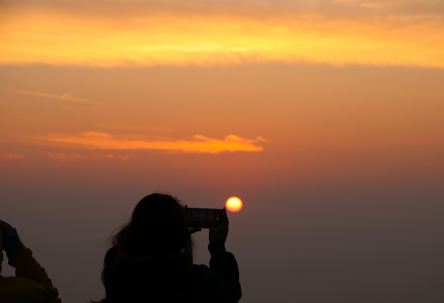 Zurück vom Touristen, der ein Foto durch intelligente Telefonsonnenaufgang- und -landschaftsansicht macht