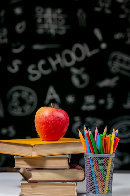 Foto zurück zum schulhintergrund mit büchern, stiften und apfel auf weißem tisch