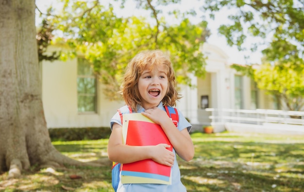 Zurück zum Schulkind mit Rucksäcken, die im Park in der Nähe von Schülern mit Büchern und Rucksäcken stehen