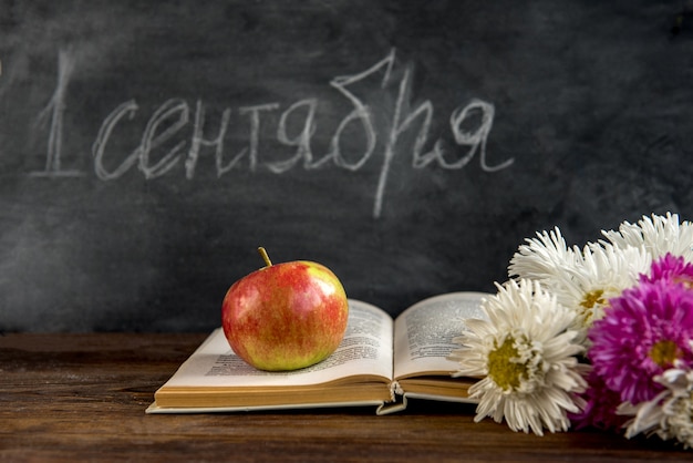 Zurück zum Schulkonzept. Buch und Astra Blumen auf Tafel. 1. September Tag.