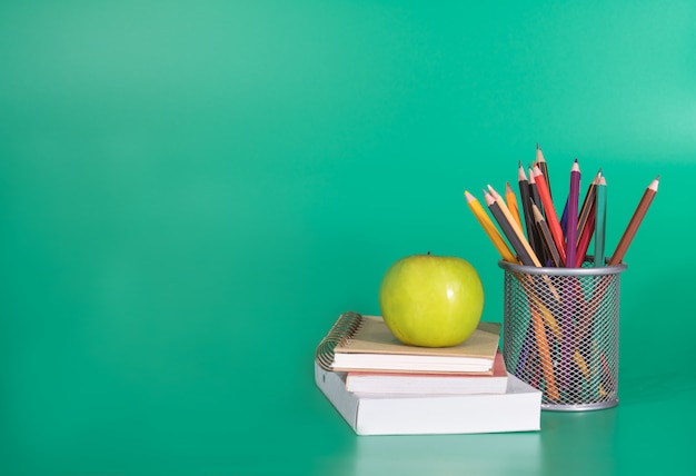 Zurück zum schulkonzept. grüner apfel auf dem buch mit schulmaterial