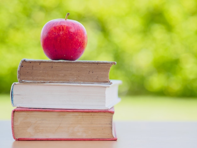 Zurück zum Schulkonzept. Roter Apfel setzte Stapel alte Bücher.