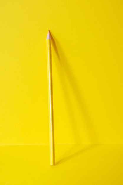 Zurück zur Schule. Ein gelber Stift steht auf einem gelben Feld. Monochromes Bild. Kreatives Konzept der Kreativität von Kindern, Zeichnen.