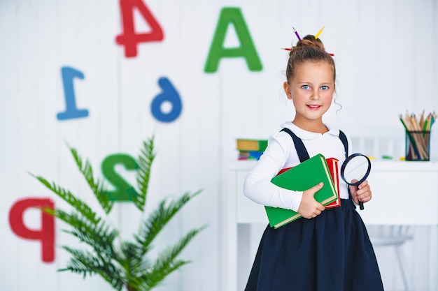 Zurück zur Schule. Glücklicher lächelnder Schüler am Schreibtisch. Kind im Klassenzimmer mit Stiften, Büchern. Kind Mädchen von der Grundschule. erster Tag des Herbstes.